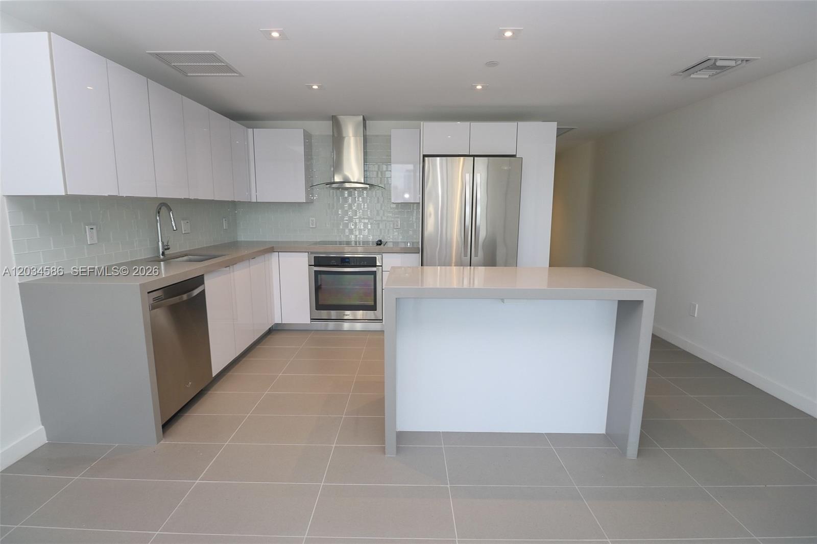 A modern kitchen features white cabinets, stainless steel appliances, and a gray quartz island — 1600 NE 1st Ave # 1010, Miami FL 33132, MIAMI, FL