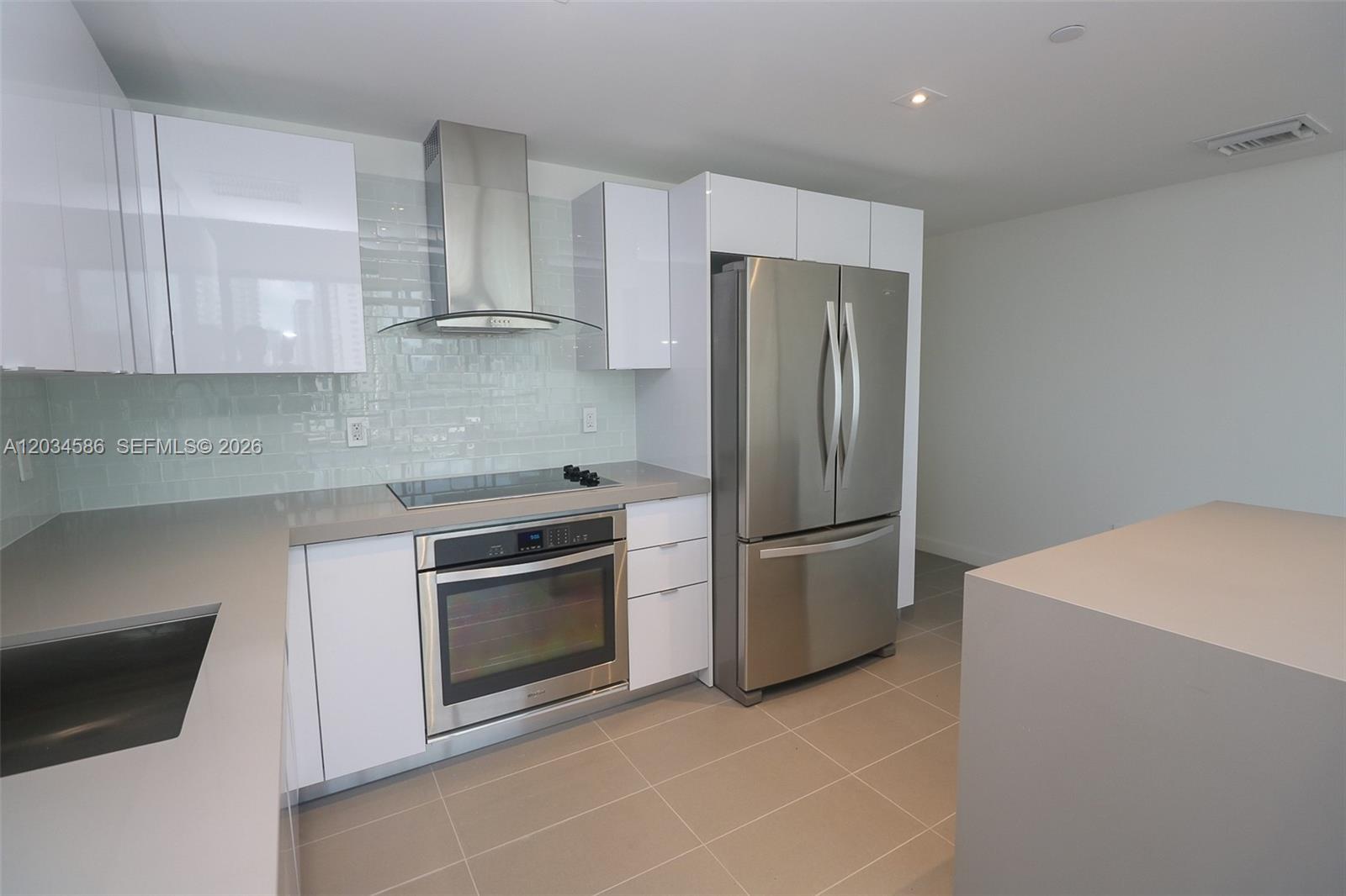 A modern kitchen features white cabinets, stainless steel appliances, and gray countertops — 1600 NE 1st Ave # 1010, Miami FL 33132, MIAMI, FL