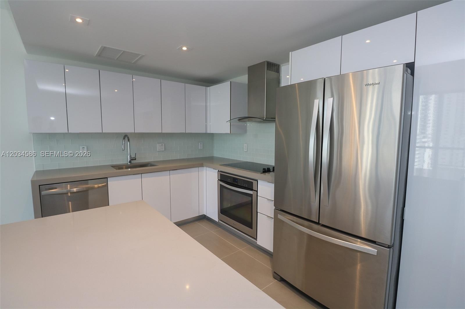 A modern kitchen features white cabinets, stainless steel appliances, and light-colored quartz countertops — 1600 NE 1st Ave # 1010, Miami FL 33132, MIAMI, FL