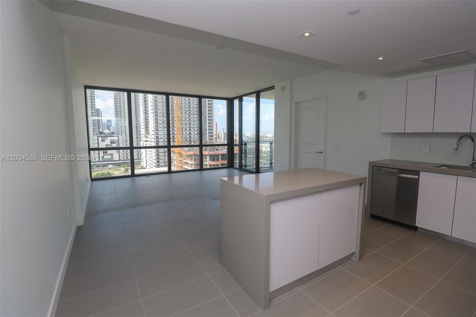 An open-concept kitchen and living area features white cabinets, a central island, and floor-to-ceiling windows — 1600 NE 1st Ave # 1010, Miami FL 33132, MIAMI, FL