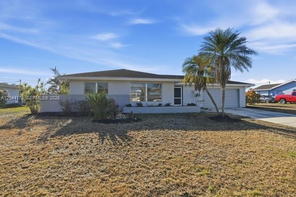A single-story house with a light-colored exterior, a garage, and a palm tree in front — 312 Hollywood, Lehigh Acres FL 33936, LEHIGH ACRES, FL
