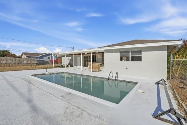 A rectangular swimming pool sits on a concrete patio behind a single-story house — 312 Hollywood, Lehigh Acres FL 33936, LEHIGH ACRES, FL
