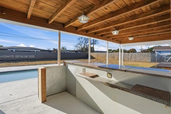 An outdoor bar with a wooden ceiling sits on a patio beside a swimming pool — 312 Hollywood, Lehigh Acres FL 33936, LEHIGH ACRES, FL