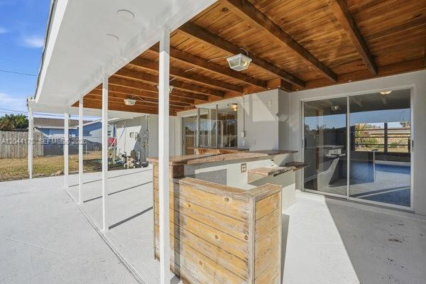 A covered patio features a wooden bar, exposed wood ceiling beams, and sliding glass doors — 312 Hollywood, Lehigh Acres FL 33936, LEHIGH ACRES, FL