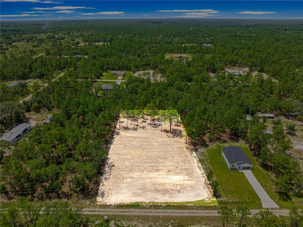 An aerial view shows a cleared, rectangular residential lot surrounded by trees and nearby houses — TBD SW 90 PLACE, DUNNELLON, FL