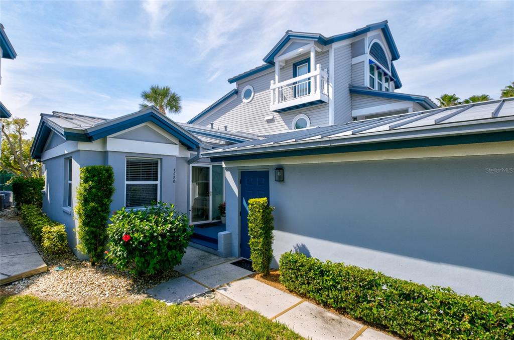 The exterior of a light blue house features a metal roof and a small balcony — 1220 SIESTA BAYSIDE DRIVE UNIT 1220-A, SARASOTA, FL