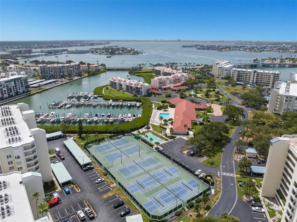 An aerial view shows tennis courts, a swimming pool, a marina, and surrounding residential buildings — 7984 SAILBOAT KEY BOULEVARD S UNIT 306, SOUTH PASADENA, FL