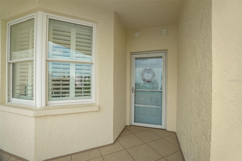 A covered entryway features a bay window with shutters and a glass storm door — 7984 SAILBOAT KEY BOULEVARD S UNIT 306, SOUTH PASADENA, FL