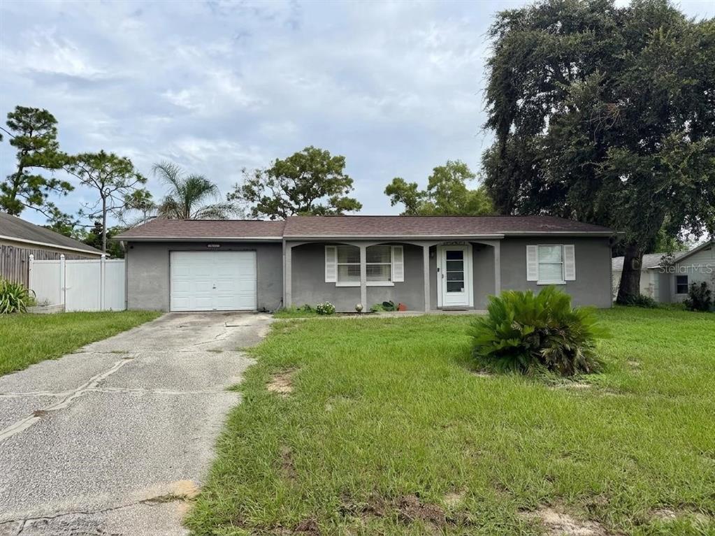 A single-story gray house with a white garage door, front porch, and a grassy yard — 4263 WELDON AVENUE, SPRING HILL, FL