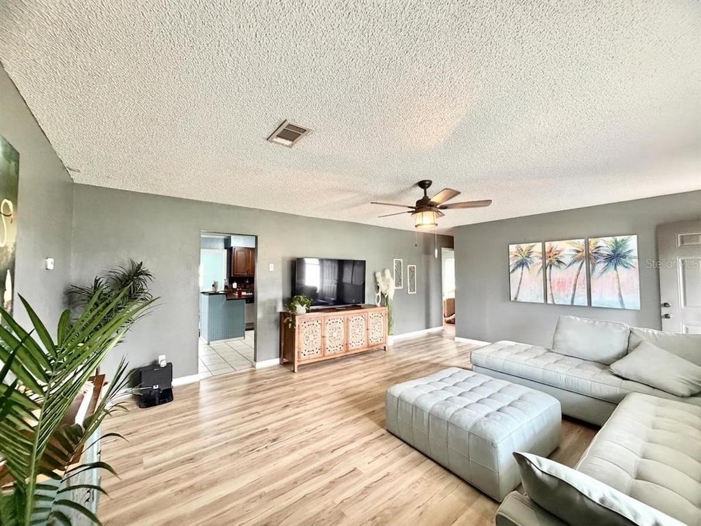 A living room with light wood floors, gray walls, a sectional sofa, and a ceiling fan — 4263 WELDON AVENUE, SPRING HILL, FL