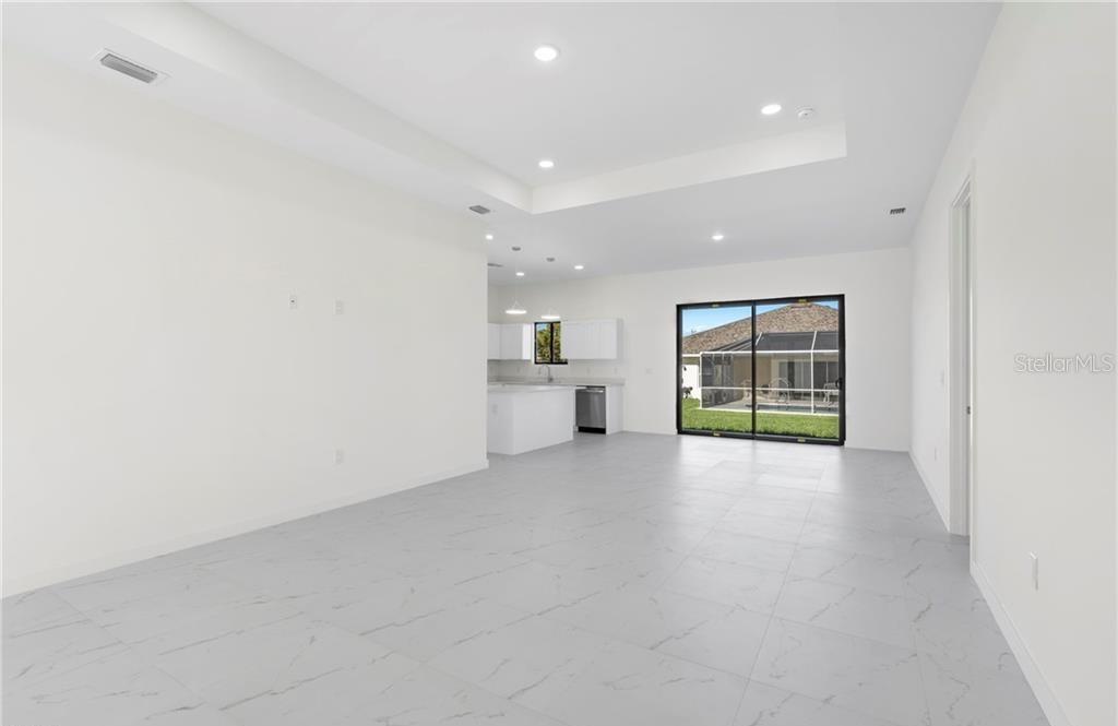 An open-concept living area features white walls, light marble-look tile flooring, and a modern kitchen — 4233 JACARANDA PARKWAY W, CAPE CORAL, FL