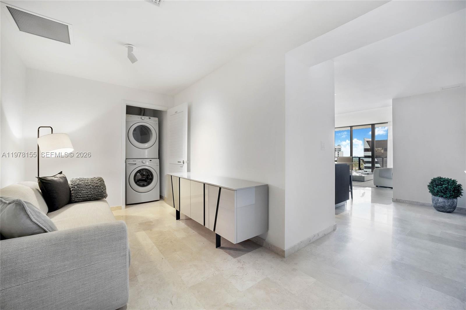 A modern room features a stacked washer and dryer, a sideboard, and light tile flooring — 88 SW 7th St # 1810, Miami FL 33130, MIAMI, FL