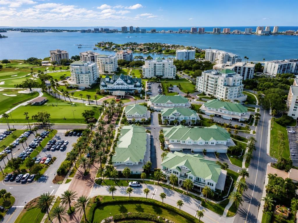 An aerial view shows a residential complex with green-roofed buildings, palm trees, and a golf course — 100 OAKMONT LANE UNIT 507, BELLEAIR, FL