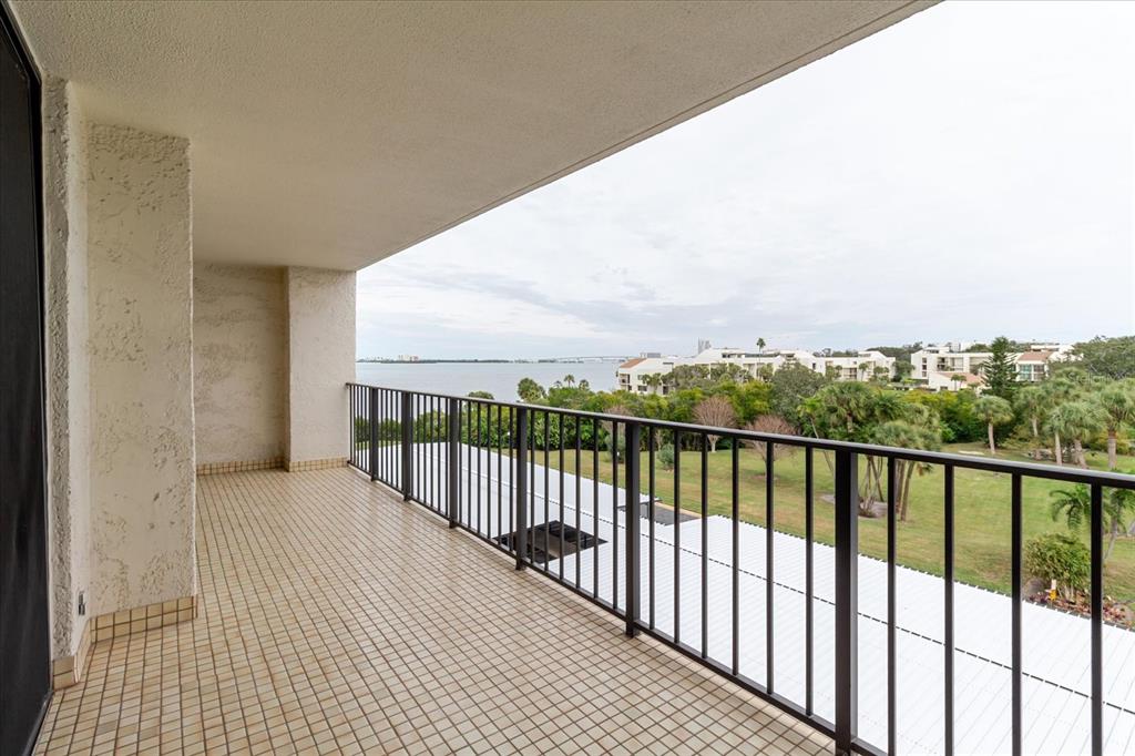 A covered balcony with tiled flooring and a black metal railing overlooks a grassy area — 100 OAKMONT LANE UNIT 507, BELLEAIR, FL