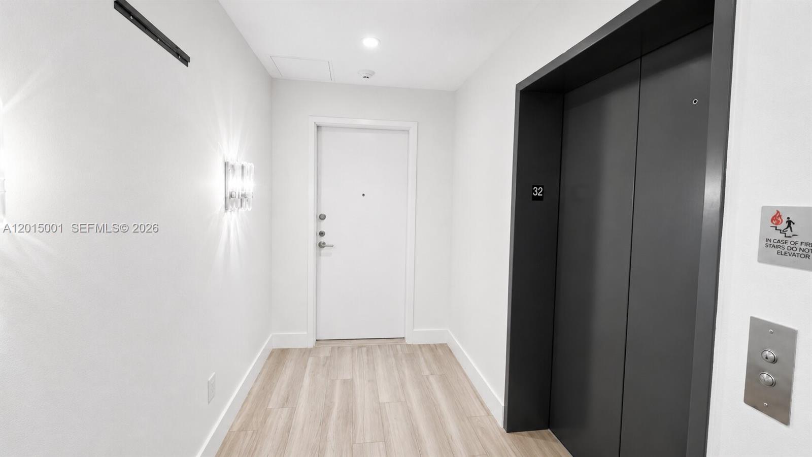 A hallway features light wood-look flooring, a white door, and a dark elevator door — 2900 NE 7th Ave # 3207, Miami FL 33137, MIAMI, FL