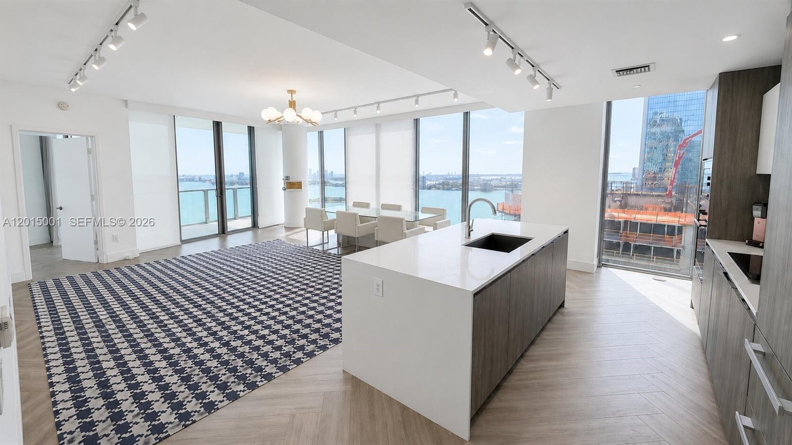 A modern open-plan kitchen and living area features floor-to-ceiling windows with water views — 2900 NE 7th Ave # 3207, Miami FL 33137, MIAMI, FL