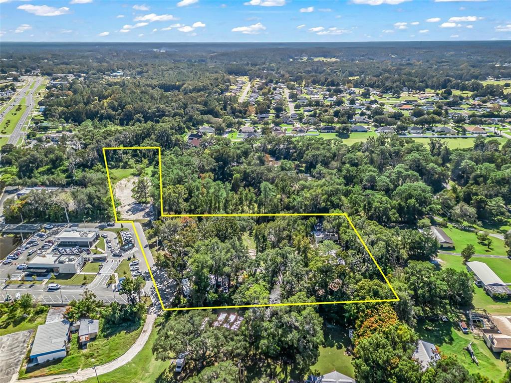 An aerial view shows a large, wooded plot of land outlined in yellow — 10366 S US HIGHWAY 441, BELLEVIEW, FL