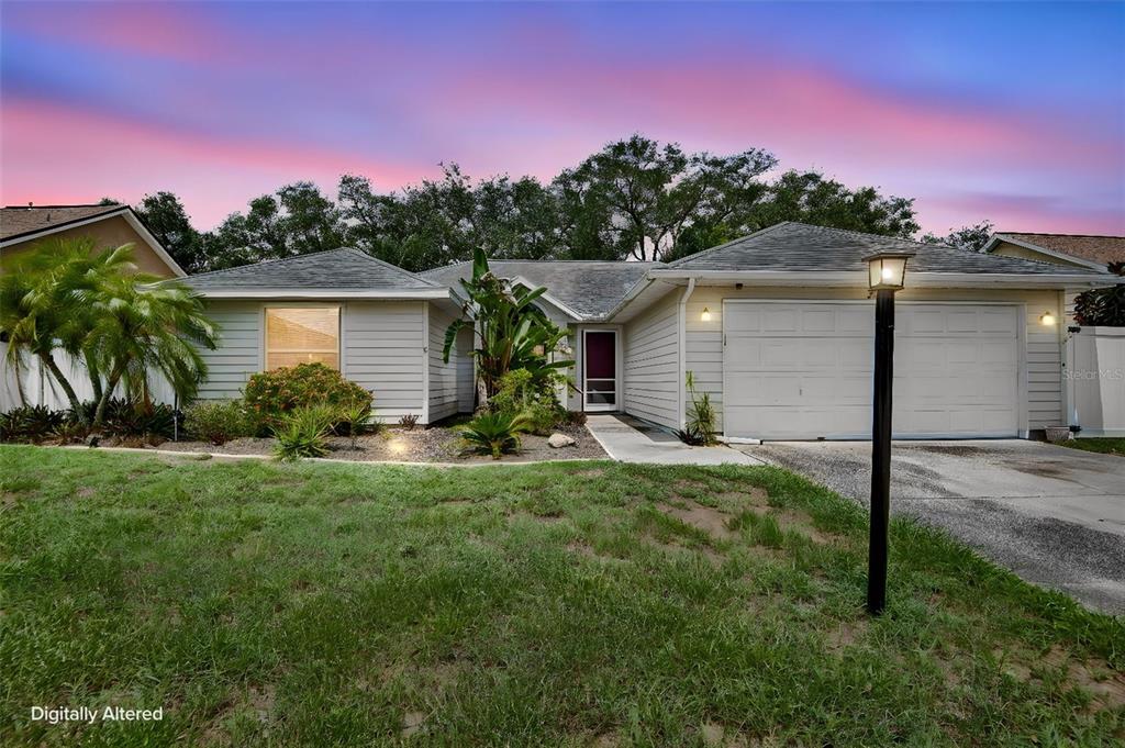 A single-story house with light siding, a two-car garage, and a landscaped front yard — 5610 33RD LANE E, BRADENTON, FL