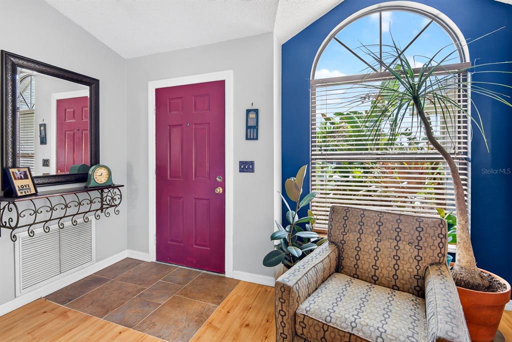 An entryway features a magenta door, a patterned armchair, a large mirror, and a window — 5610 33RD LANE E, BRADENTON, FL