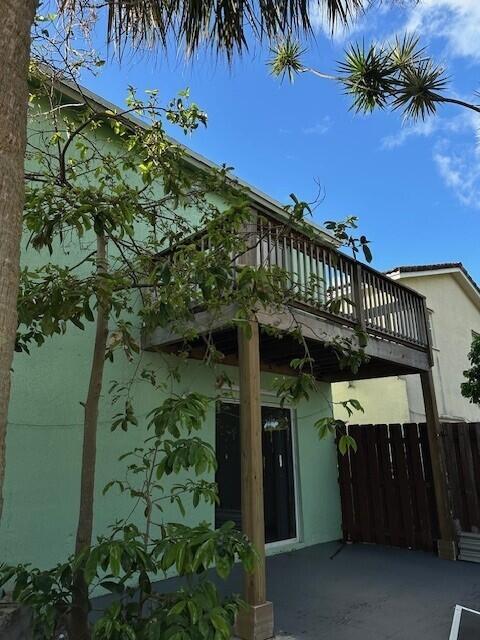 A two-story light green house features a wooden balcony supported by posts above a patio — 4172 Pine Hollow Circle, FL 33463, FL
