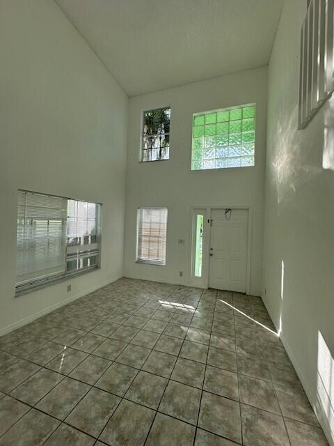 A high-ceilinged room features tiled floors, a front door, and several windows — 4172 Pine Hollow Circle, FL 33463, FL