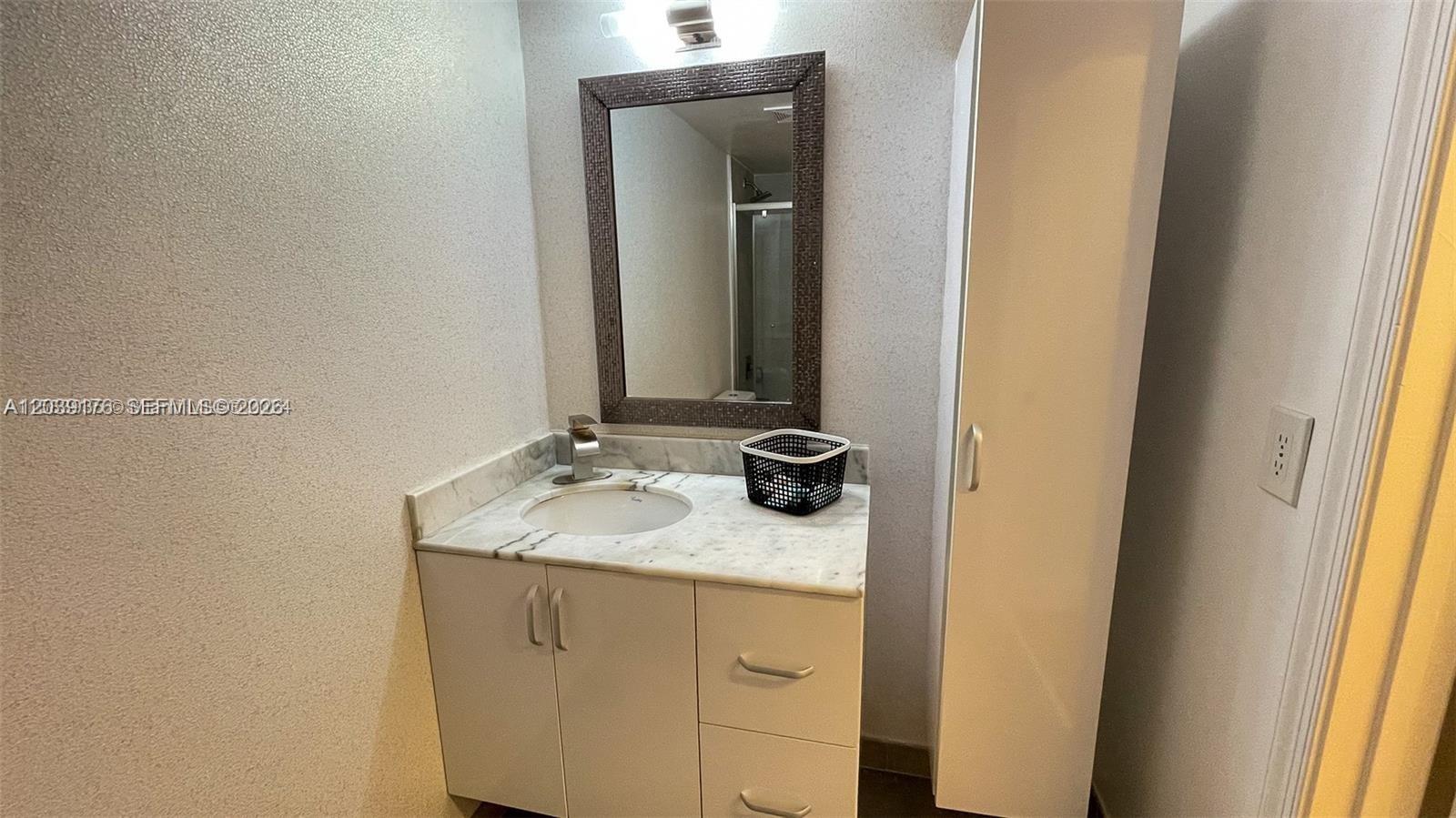 A bathroom features a white vanity with a marble countertop, a mirror, and a cabinet — 1200 Brickell Bay Dr # 1702, Miami FL 33131, MIAMI, FL