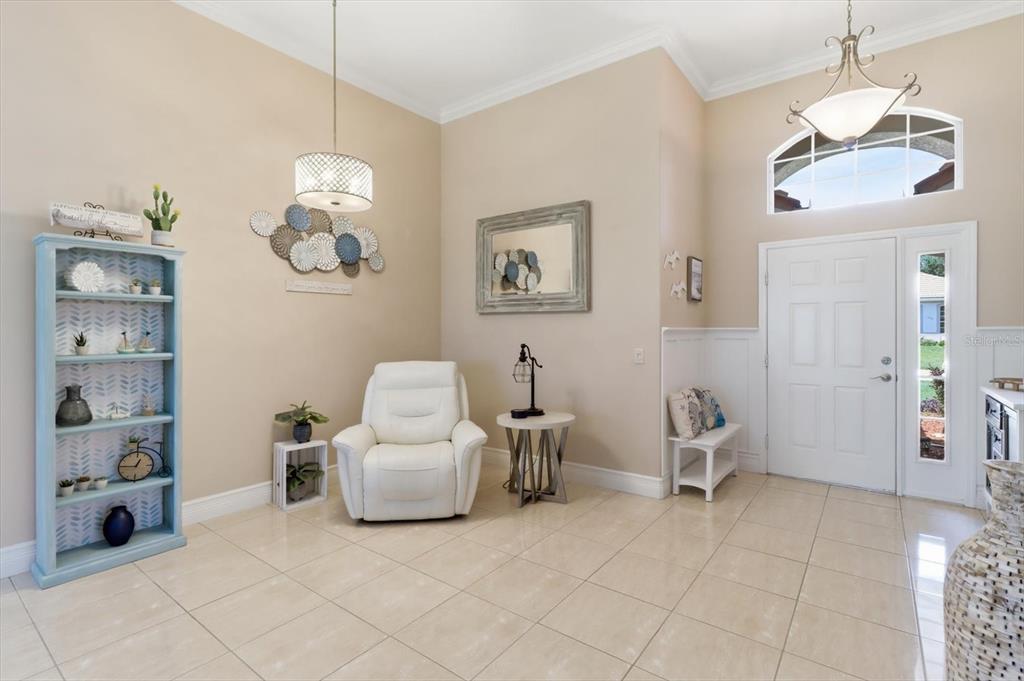 A bright entryway features a white armchair, a blue bookshelf, and tile flooring — 1257 W SKYVIEW CROSSING DRIVE, HERNANDO, FL