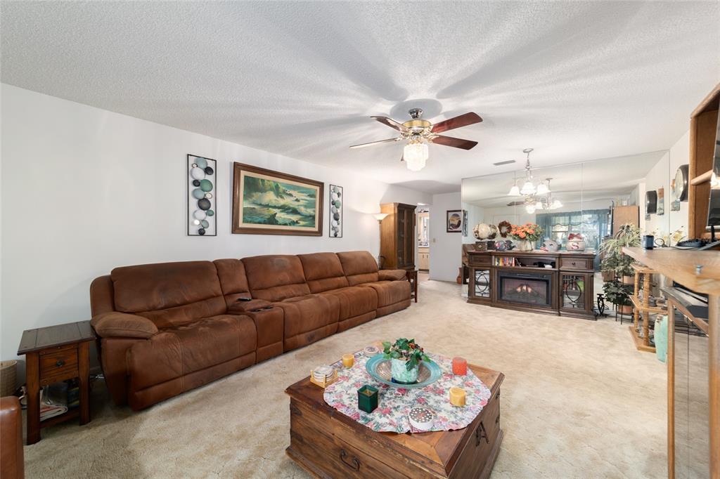 A living room features a large brown sectional sofa, a coffee table, and mirrored walls — 9233 SW 83RD TERRACE UNIT D, OCALA, FL