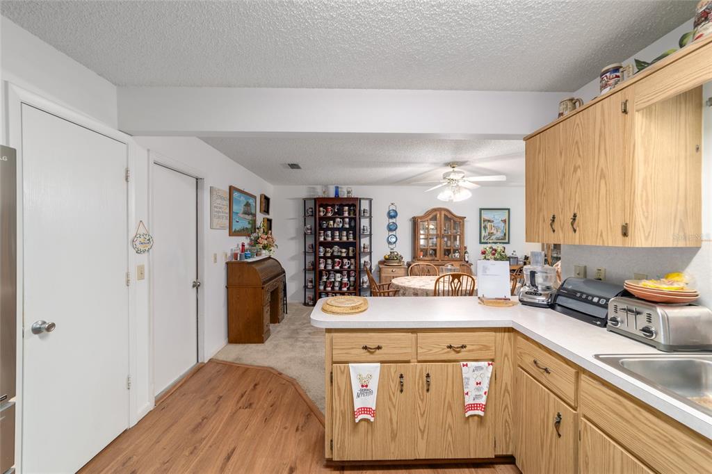 A kitchen with oak cabinets and a breakfast bar overlooks a carpeted dining area — 9233 SW 83RD TERRACE UNIT D, OCALA, FL