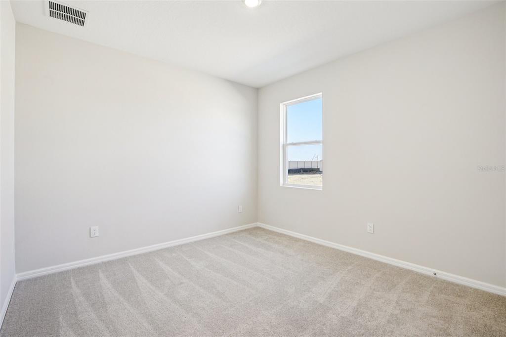 An empty bedroom with beige carpet, light-colored walls, and a single window — 5911 FRESH FLORA DRIVE, WIMAUMA, FL