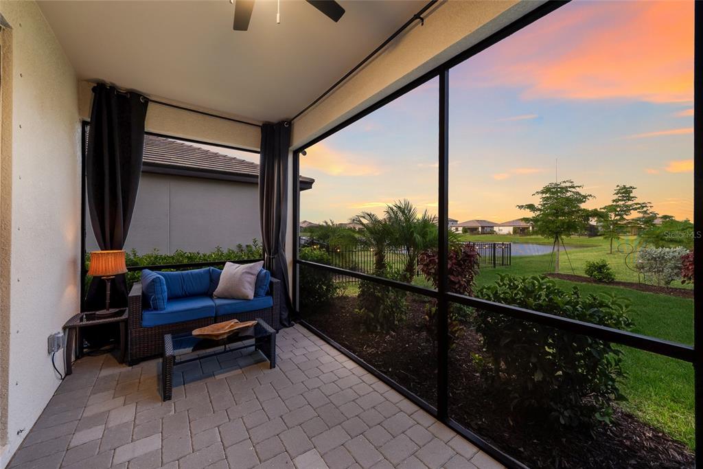 A screened-in patio with a blue sofa, coffee table, and views of a grassy yard — 15041 SERENE SHORES LOOP, BRADENTON, FL
