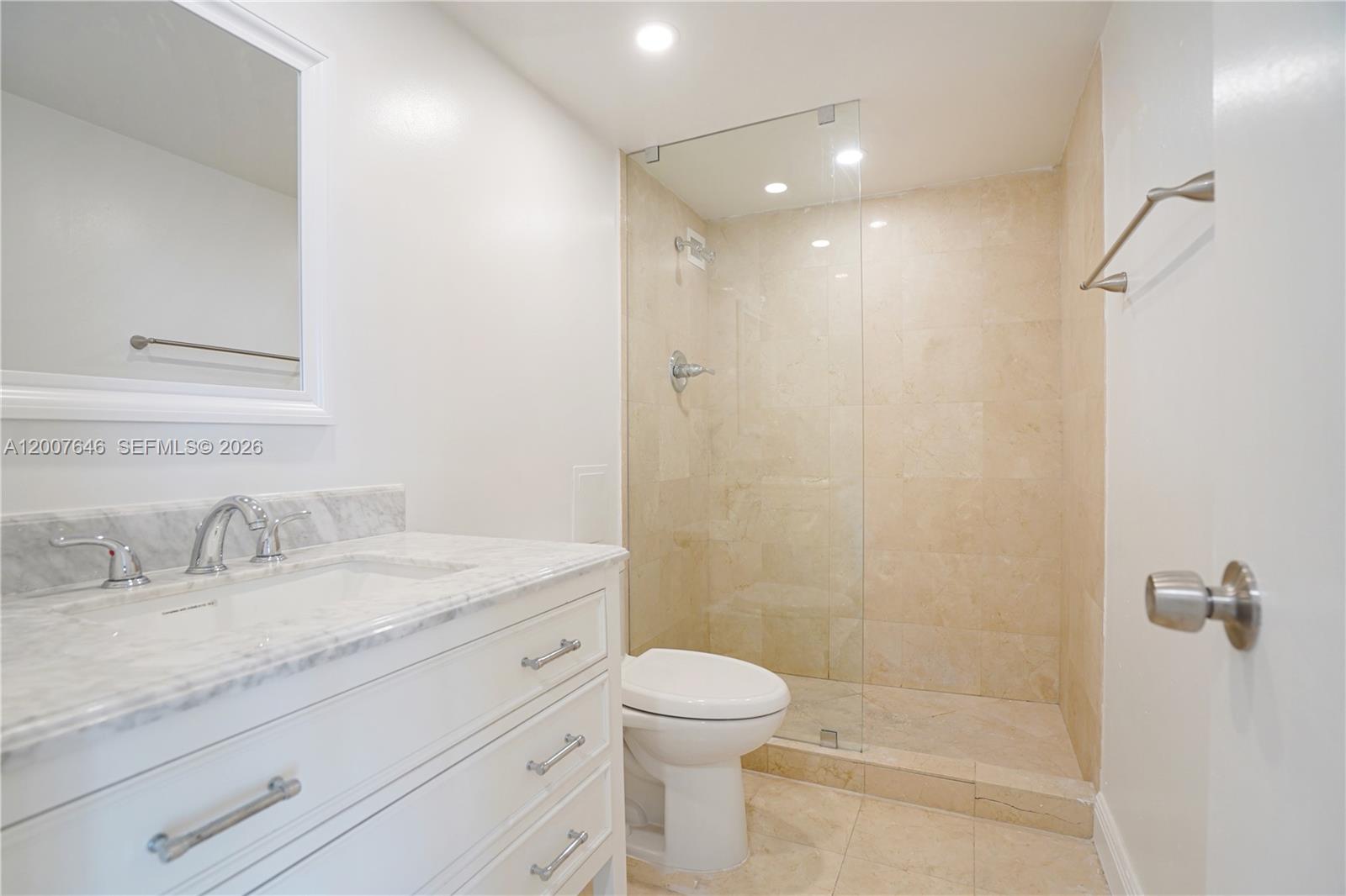 A bathroom features a white vanity with a marble countertop, a toilet, and a glass-enclosed shower — 5101 Collins Ave # 14F, Miami Beach FL 33140, MIAMI BEACH, FL