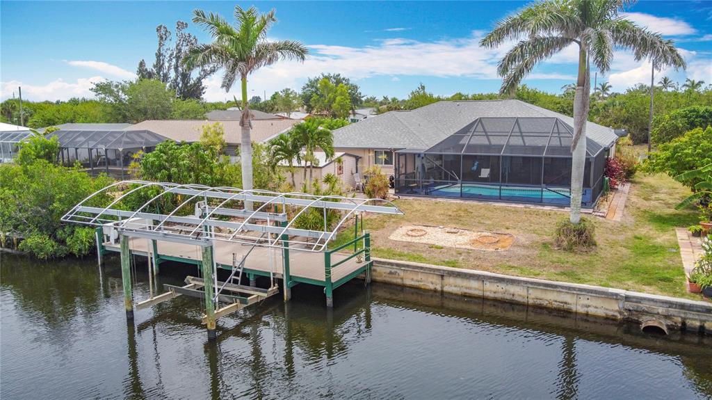 An aerial view of a waterfront house with a screened pool and a boat lift — 18790 COUNTRYMAN AVENUE, PORT CHARLOTTE, FL
