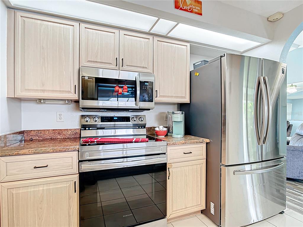 A kitchen features light wood cabinets, stainless steel appliances, and granite countertops — 18790 COUNTRYMAN AVENUE, PORT CHARLOTTE, FL