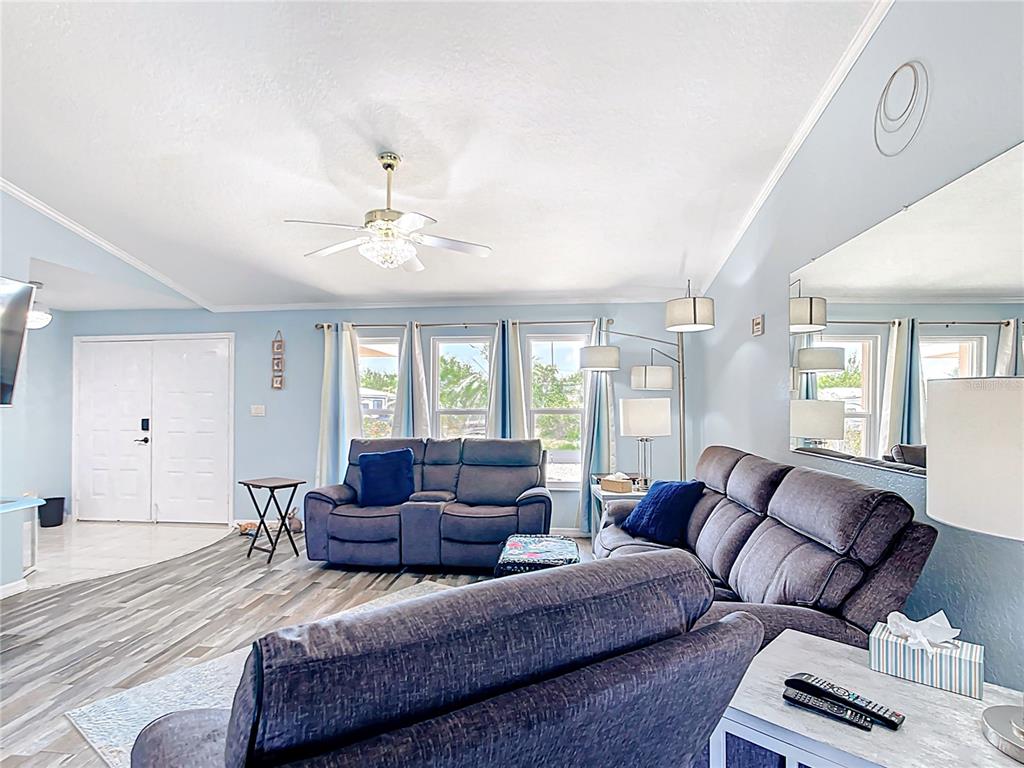 A living room features gray sofas, a ceiling fan, and wood-look flooring — 18790 COUNTRYMAN AVENUE, PORT CHARLOTTE, FL