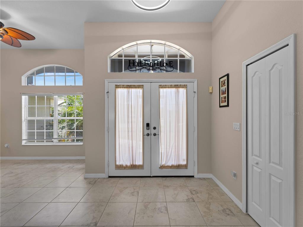 An entryway features tiled floors, double front doors with curtains, and an arched transom window — 2288 PRAGUE LANE, PUNTA GORDA, FL