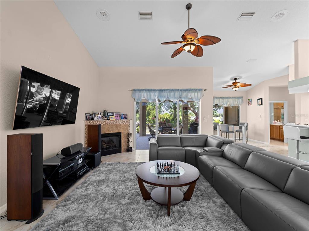 A living room features a grey sectional sofa, a fireplace, and a large television — 2288 PRAGUE LANE, PUNTA GORDA, FL