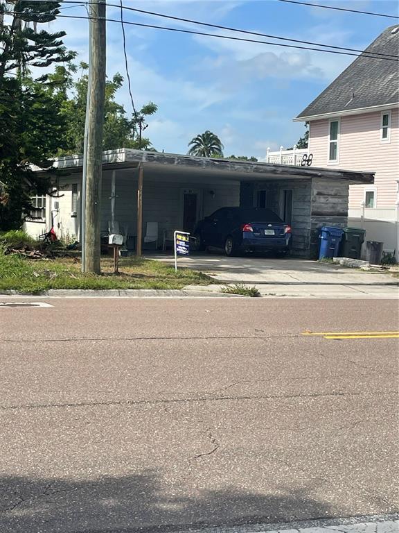 A single-story house with a flat roof and a carport sits next to a pink building — 2445 WEBBER STREET, SARASOTA, FL
