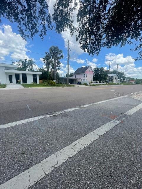 A street-level view shows a modern white building and a pink house under a blue sky — 2445 WEBBER STREET, SARASOTA, FL