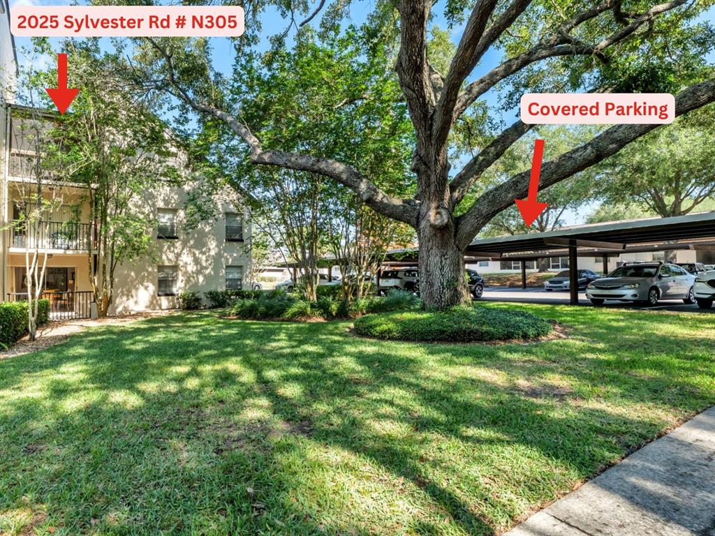 An exterior view of a multi-story apartment building with a lawn and covered parking area — 2025 SYLVESTER RD UNIT N305, LAKELAND, FL