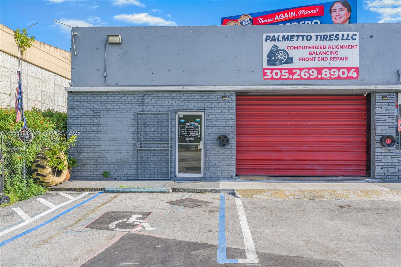 The exterior of a gray brick commercial building features a red roll-up door and signage — 7790 SW 26th St, Miami FL 33155, MIAMI, FL