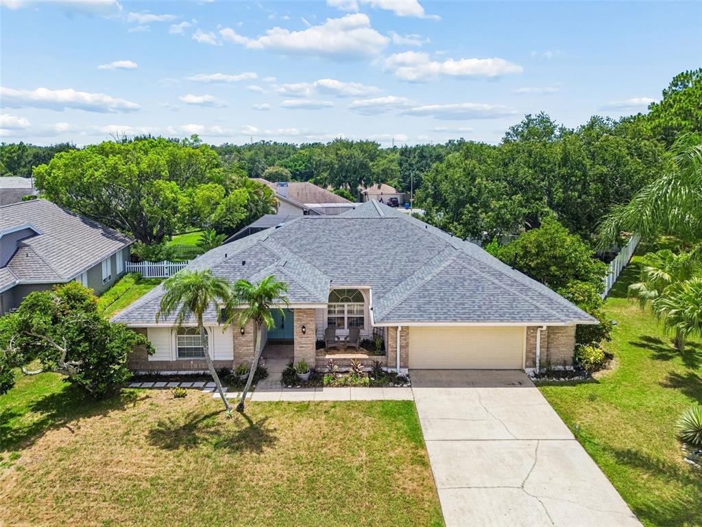 An aerial view shows a single-story house with a gray shingled roof and driveway — 1776 WOOD THRUSH WAY, PALM HARBOR, FL