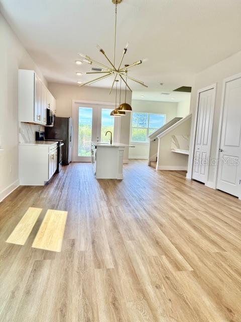 A kitchen with white cabinets, a central island, and a modern chandelier over wood flooring — 1600 BIRCHFIELD COVE, OVIEDO, FL
