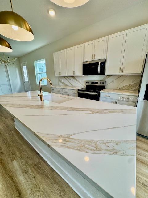 A modern kitchen features a large white quartz island with gold veining and white cabinetry — 1600 BIRCHFIELD COVE, OVIEDO, FL