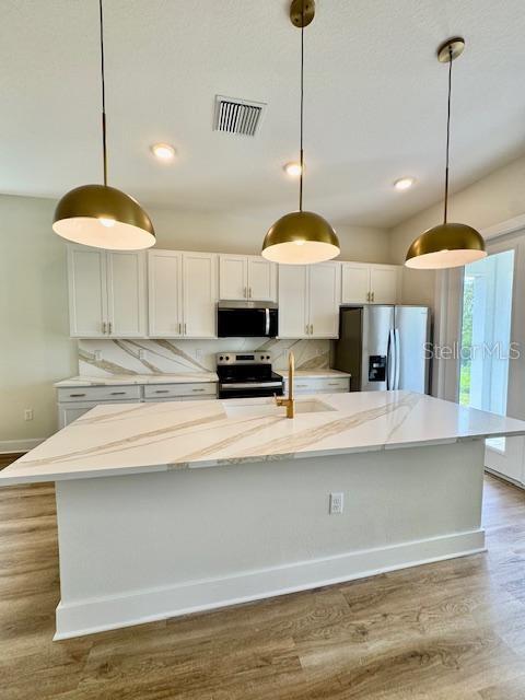 A kitchen features a large white quartz island, gold pendant lights, and white cabinetry — 1600 BIRCHFIELD COVE, OVIEDO, FL