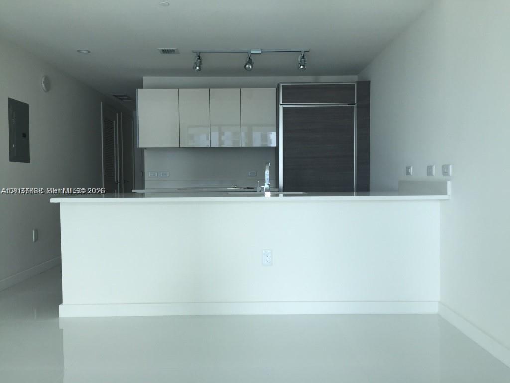 A modern kitchen features white cabinets, a dark refrigerator, and a white breakfast bar — 1100 S MIAMI AVE # 3811, Miami FL 33130, MIAMI, FL