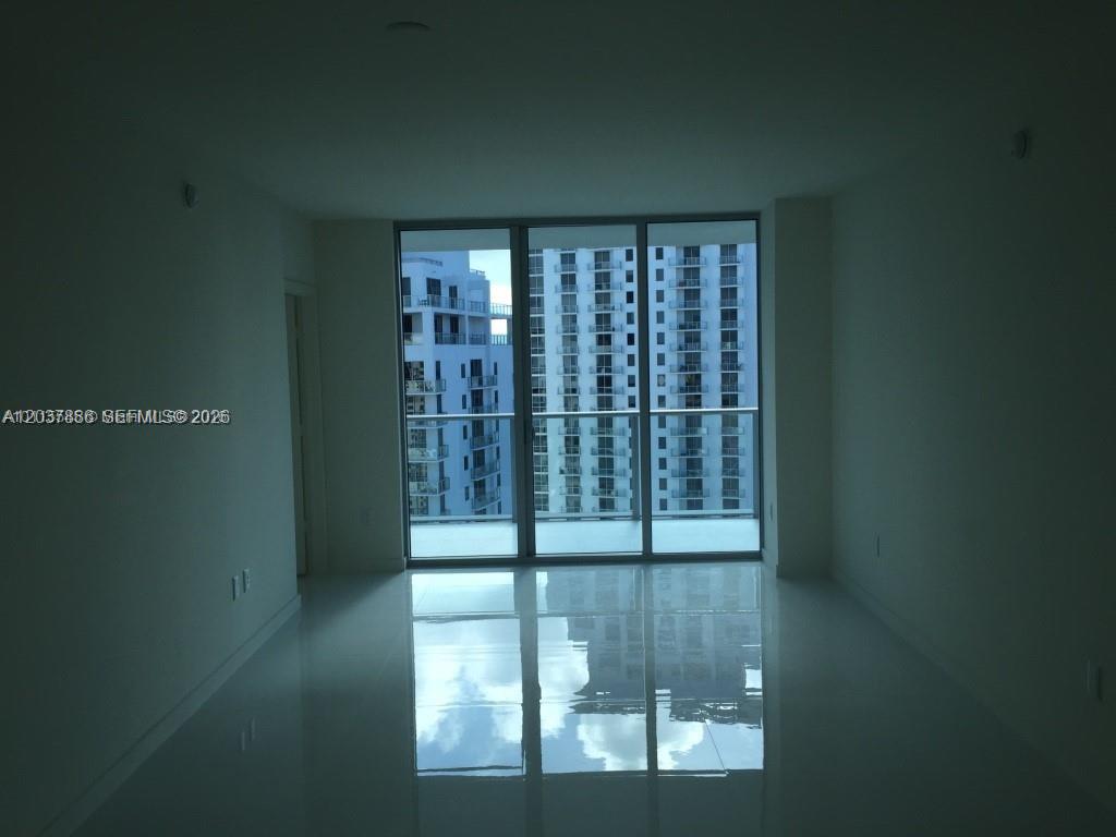 An empty room with white walls, glossy tile floors, and floor-to-ceiling windows overlooking buildings — 1100 S MIAMI AVE # 3811, Miami FL 33130, MIAMI, FL