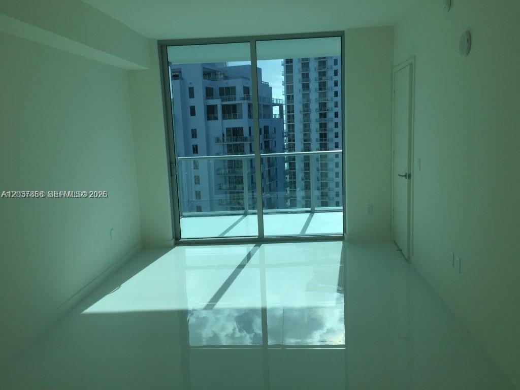 An empty room with white tile floors features a sliding glass door leading to a balcony — 1100 S MIAMI AVE # 3811, Miami FL 33130, MIAMI, FL
