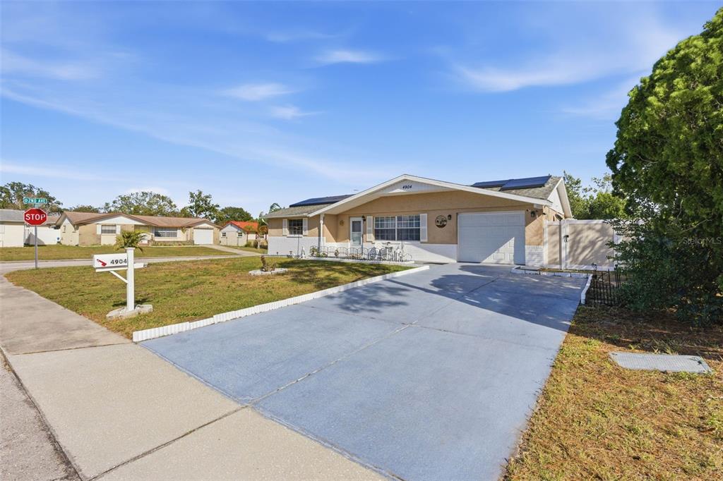 A single-story house with a concrete driveway, a garage, and a lawn under a blue sky — 4904 ELMWOOD STREET, NEW PORT RICHEY, FL