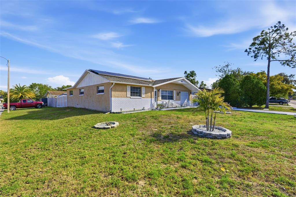 A single-story house with a tan stucco exterior, white brick base, and rooftop solar panels — 4904 ELMWOOD STREET, NEW PORT RICHEY, FL